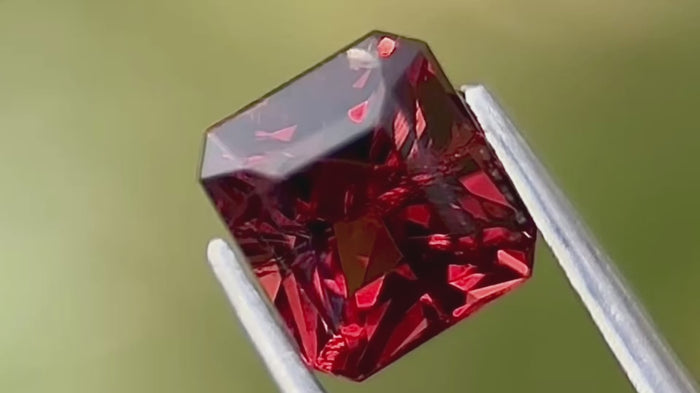 Burma origin red natural spinel gemstone, 2.05 carats, cushion-cut, dimensions 7.1x6.4x5.0mm, in natural daylight with plain green background. 